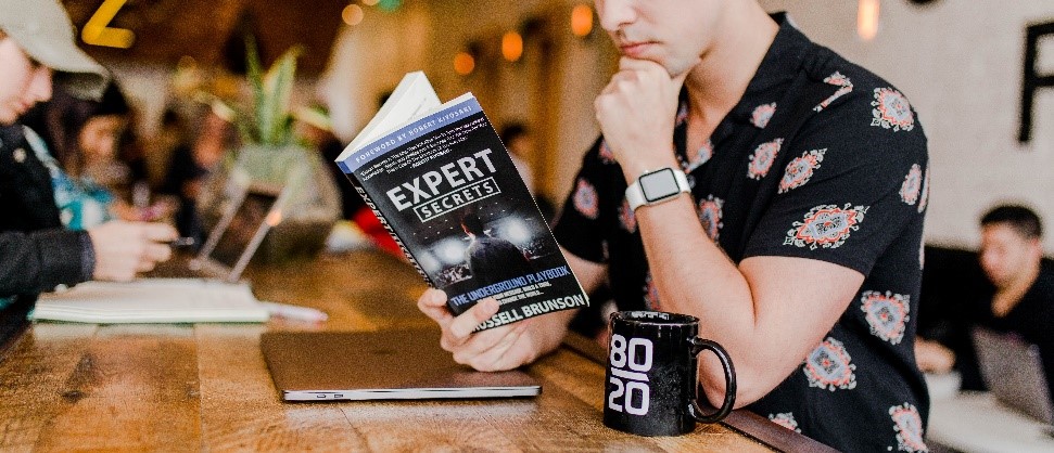 a man is reading a book with title Expert Secret