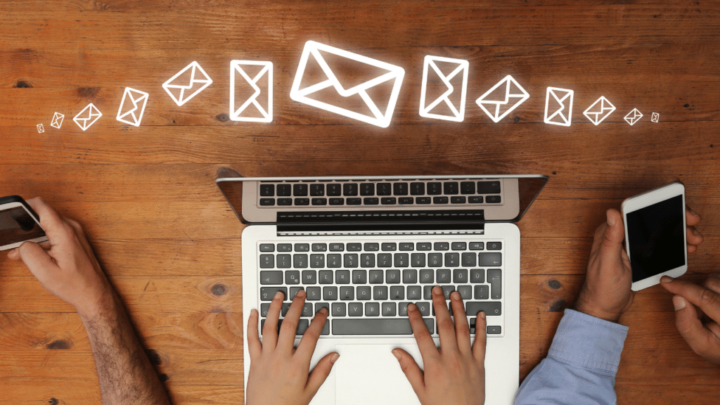 person typing at computer on desktop with animated email envelopes flying through the screen
