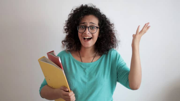 a women with curly hair and glasses laughing and cheering for something