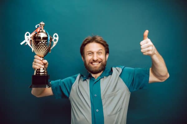 man is giving thumps up and cheering with his winning trophy